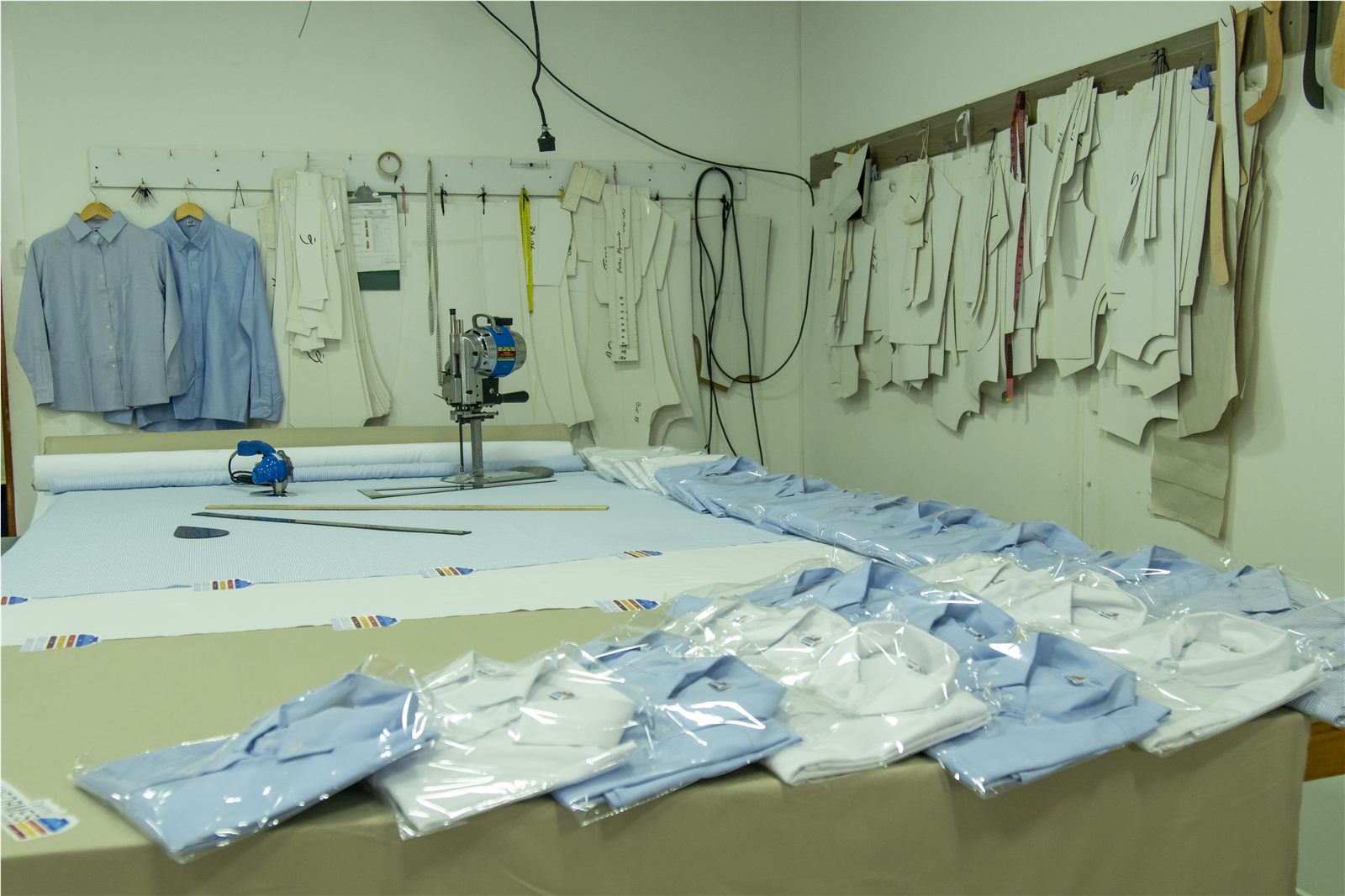 Taller de confección de uniformes CUDSAS: mesa de corte con camisas empacadas y patrones de molde